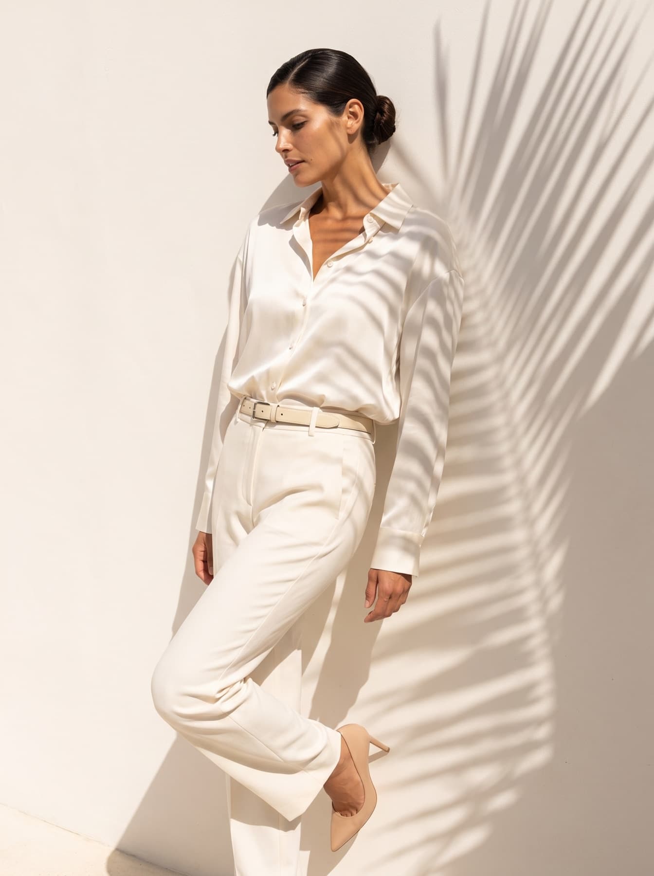 Cream silk shirt and tailored trousers, palm shadow on plaster wall